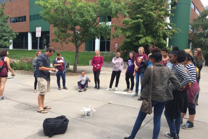 Middle school students watching a graduate student demonstrate a drone